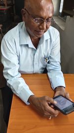 Midsection of man using smart phone on table