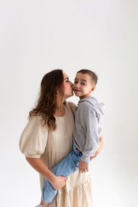 Portrait of smiling mother and daughter against white background