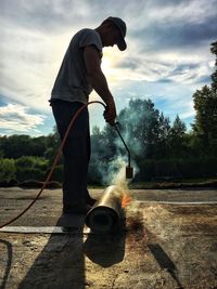 Full length of man working with fire on field against sky