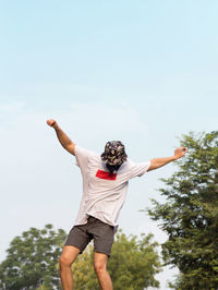 Low angle view of man with arms outstretched against sky