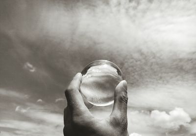 Close-up of person holding ice against sky