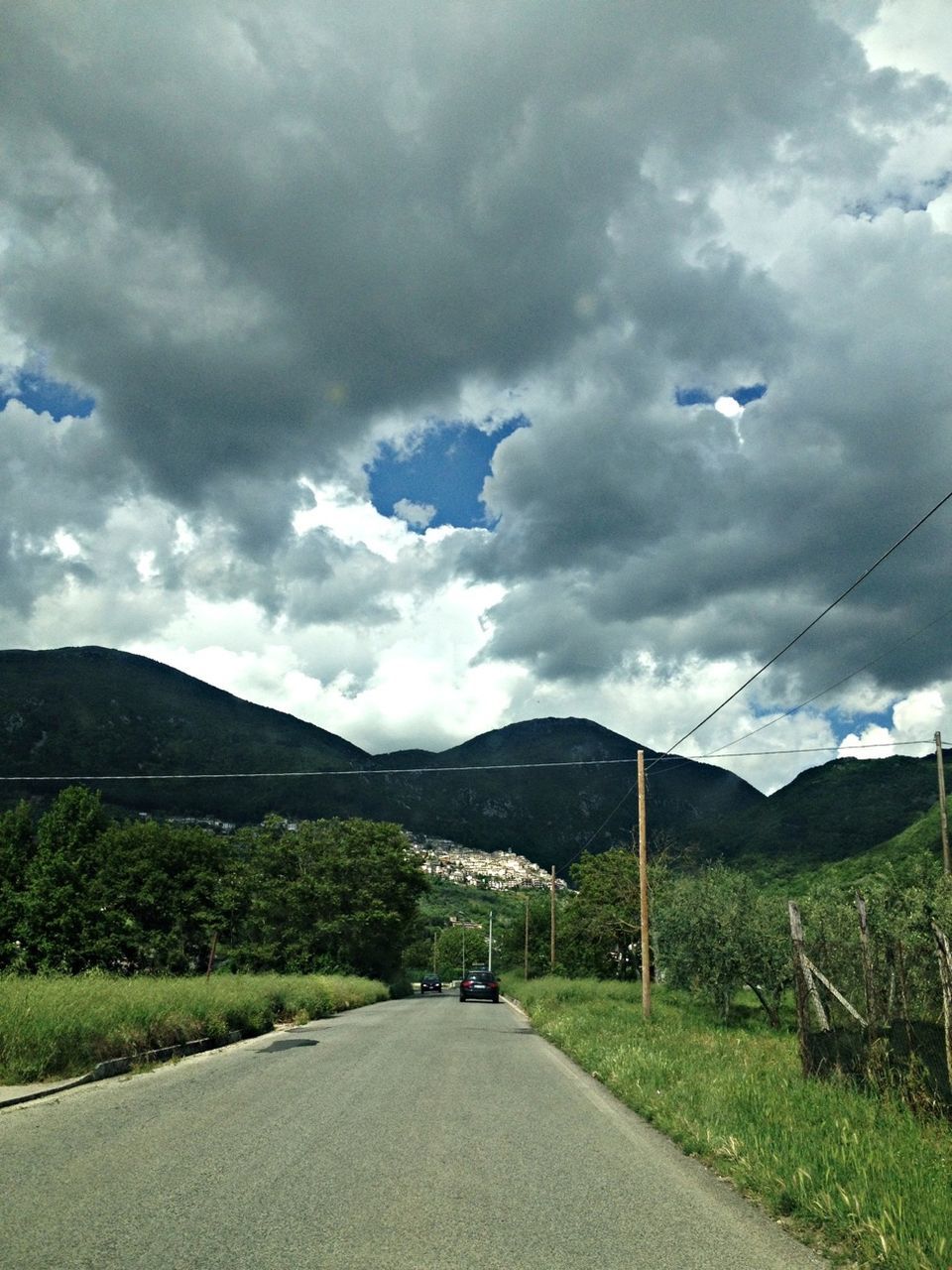 mountain, sky, road, the way forward, cloud - sky, mountain range, transportation, cloudy, landscape, country road, cloud, tranquil scene, tranquility, scenics, beauty in nature, nature, diminishing perspective, non-urban scene, road marking, grass