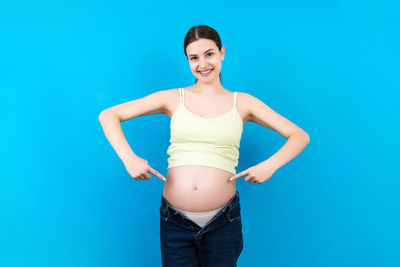 Portrait of a smiling young woman against blue background