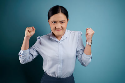 Portrait of a smiling young woman against blue background