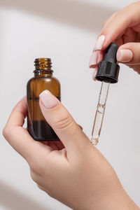 Close-up of hand holding bottle against white background