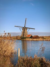 Traditional windmill on landscape against clear blue sky