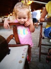 Cute girl standing by chair outdoors