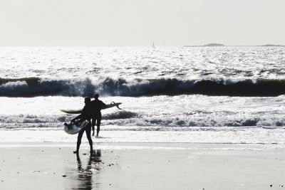 Man with surfboard walking on beach
