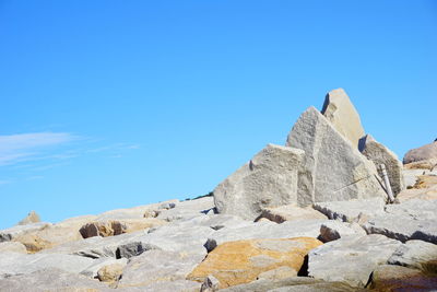 Low angle view of rocks against clear blue sky