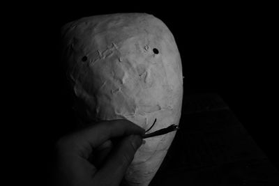 Close-up of hand holding paper over black background