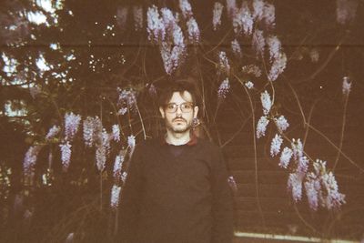 Portrait of man standing against tree