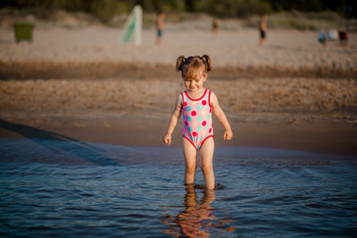 Cute girl standing in sea at beach