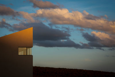 House on field against sky at sunset