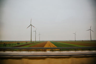 Wind turbines on field against sky