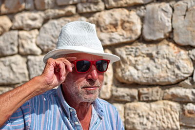 Portrait of man wearing sunglasses against brick wall