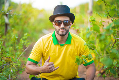 Portrait of young man wearing sunglasses while standing against plants