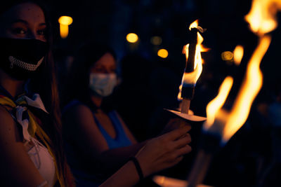 Midsection of man holding lit candles at night