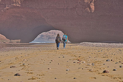 Rear view of people walking on rock