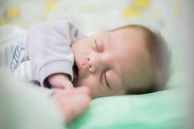 Close-up of cute baby boy sleeping on crib
