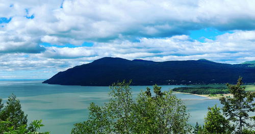 Scenic view of sea by mountains against sky