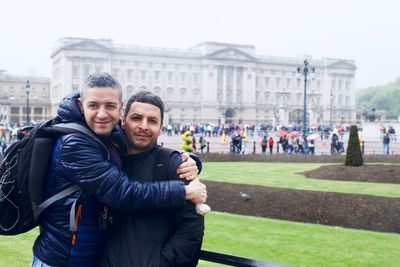 Portrait of happy friends standing against buckingham palace