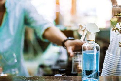 Midsection of man pouring drink in glass bottle on table