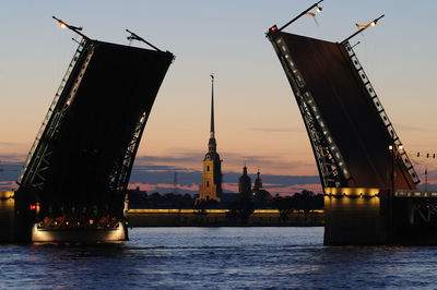 Cranes in city at sunset