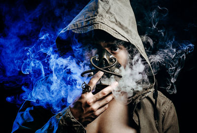 Young man with gas mask against black background