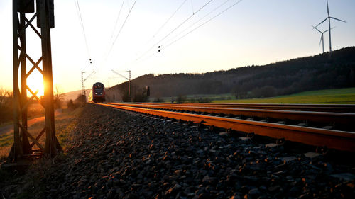 Train on railroad tracks against sky during sunset