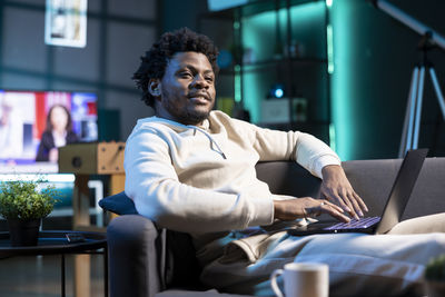 Young man using mobile phone while sitting at home