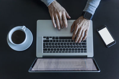 Top view of businessman at desk with laptop, smartphone and cup of coffee