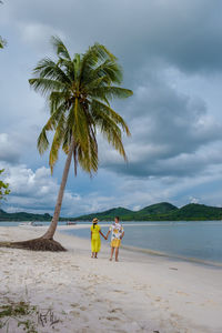 Rear view of woman standing at beach against sky