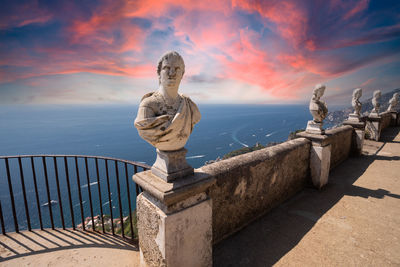 Statue by sea against sky during sunset