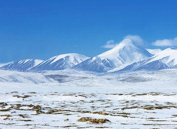 Scenic view of snowcapped mountains against blue sky