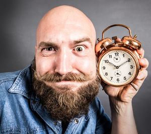 Close-up portrait of man listening clock on head