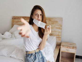 Portrait of beautiful woman sitting on bed at home