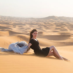 Woman sitting on sand dune in desert