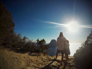 Rear view of a man walking on landscape at sunset
