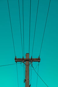 Low angle view of electricity pylon against blue sky