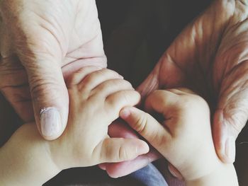 Close-up of father holding baby hand