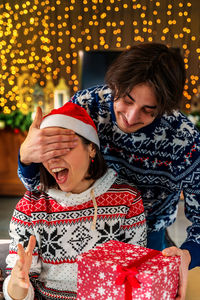 Pretty young woman surprisedly receives a christmas gift box from her boyfriend