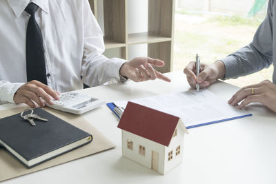 Midsection of colleagues doing paperwork at desk in office