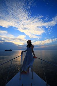 Woman standing on boat sailing in sea against sky