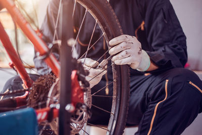 Midsection of mechanic repairing bicycle in garage