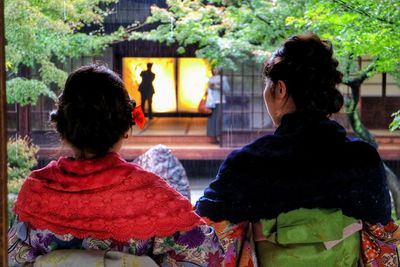 Rear view of women in kimono standing at japanese garden by temple