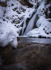 Scenic view of snow covered landscape and waterfall 
