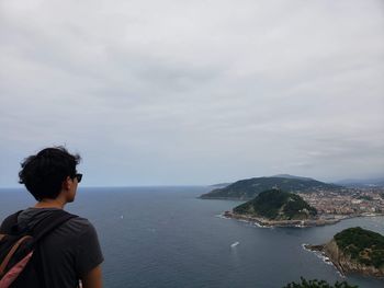 Rear view of man looking at sea against sky