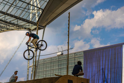 Low angle view of men on bicycle against sky