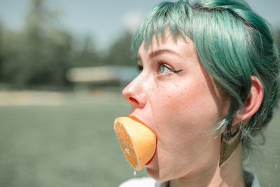 Close-up of thoughtful woman having orange while standing outdoors