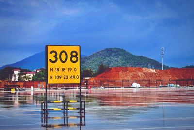 Information sign by swimming pool against sky